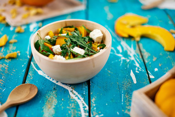 Healthy pumpkin salad with cheese and arugula served in wooden dishes