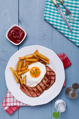 English breakfast with grilled ham, fried egg and french fries.