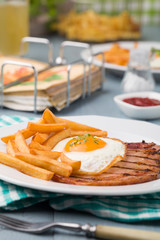 Fototapeta na wymiar English breakfast with grilled ham, fried egg and french fries.