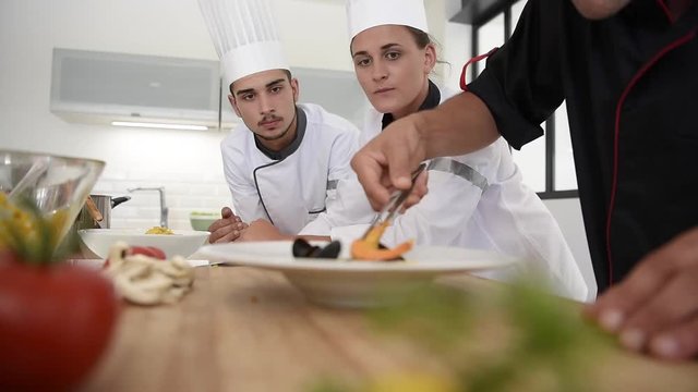 Young chefs presenting dish to teacher