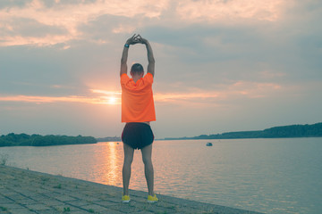 Fototapeta na wymiar Urban jogger stretching near the river.