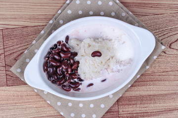 Black bean and sticky rice in sweet coconut cream topped coconut milk on gray and wood.Top view.