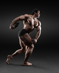 Handsome muscular bodybuilder posing over black background.