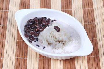 Black bean and sticky rice in sweet coconut cream topped coconut milk on brown. Side view.