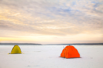 Bright tents camping of the expedition on the ice of the Northernat sunset. Wild adventure tours and trekking in the harsh winters of Northern nature. Courage and fortitude of traveler. 