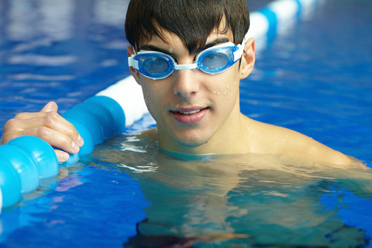 Face of a man in goggles above the water in the swimming pool