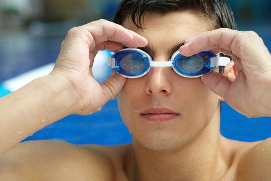 Portrait of a swimmer putting on his goggles in the swimming pool
