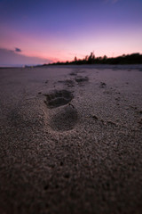 Impronte sulla sabbia di una persona dopo il tramonto. 