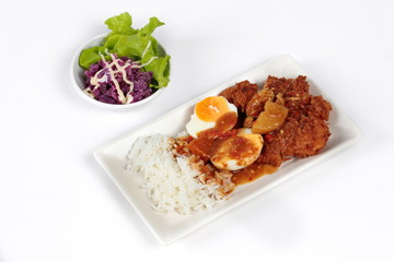 Rice with deep fried chicken and boiled halves eggs topped  Japanese yellow  curry  with butter mashed potatoes salad on white. Side view