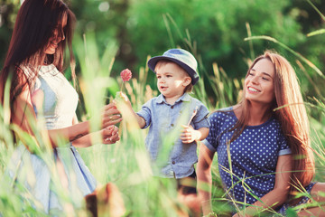Beautiful happy family resting in nature. Two women - mom and aunt play with a boy in the Park....