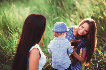 Beautiful happy family resting in nature. Two women - mom and aunt play with a boy in the Park....