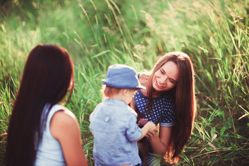 Beautiful happy family resting in nature. Two women - mom and aunt play with a boy in the Park. soft focus