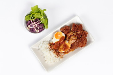 Rice with deep fried chicken and boiled halves eggs topped  Japanese yellow  curry with butter mashed potatoes salad on white. Top view