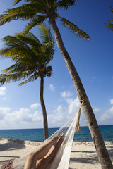 female legs in a hammock on background of ocean and sky