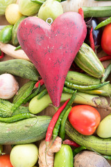Wooden red heart on top of various fresh organic healthy vegetables 