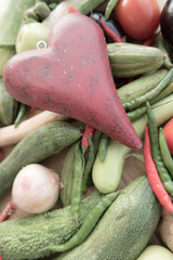 Wooden red heart on top of various fresh organic healthy vegetables 