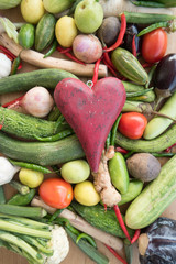 Wooden red heart on top of various fresh organic healthy vegetables 