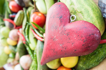 Wooden red heart on top of various fresh organic healthy vegetables 