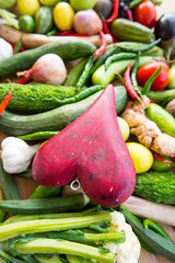 Wooden red heart on top of various fresh organic healthy vegetables 