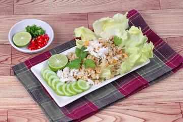 Fried rice with crab topped streamed crab,halve green lemon,sliced cucumber,lettuce and coriander  served  spicy  sour filling side dish  on wood. Side view.