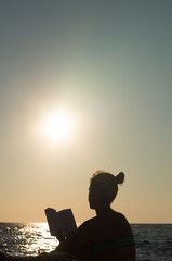 woman reading book on the beach