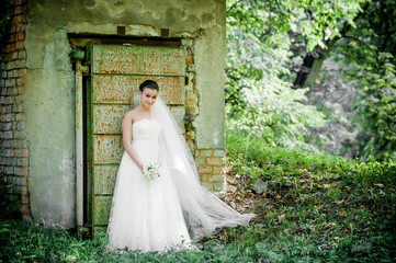 beautiful girl in wedding dress near old door