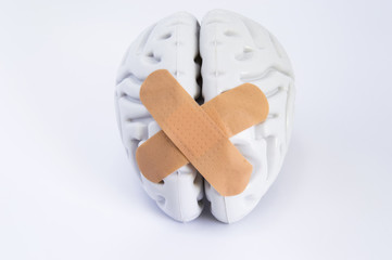 Hemispheres of human brain, stuck together using beige adhesive tape, lying on white background. The idea for visualizing treatment of neurological diseases such as the broken brain syndrome and other