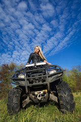 Elegant blonde woman riding extreme quadrocycle ATV on summer fi