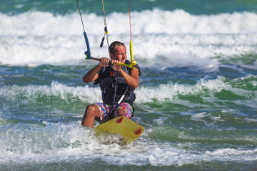 Athletic man riding on kite surf board in sea waves