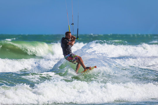 Athletic man riding on kite surf board in sea waves