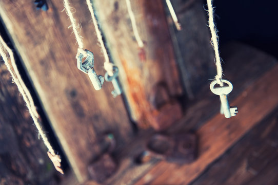 Many keys hanging on a string. Wooden background. Selective focus