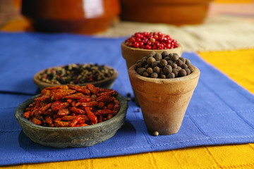 Dried red, hot chili, black, white peppers in old clay bowls in