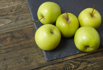 Green apples on a rustic wood and slate background