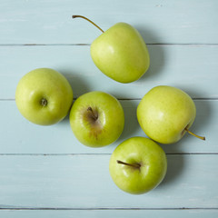 Aerial view of green apples on a painted wooden background