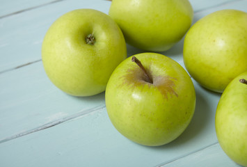 Green apples on a blue painted wooden table background