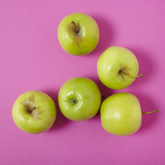 Aerial view of green apples on a bright pink background