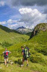 Zwei Männer wandern mit schweren Rucksäcken im Gebirge
