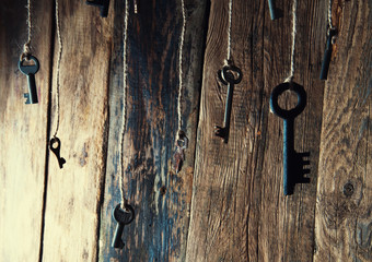 Many keys hanging on a string. Wooden background. Selective focus