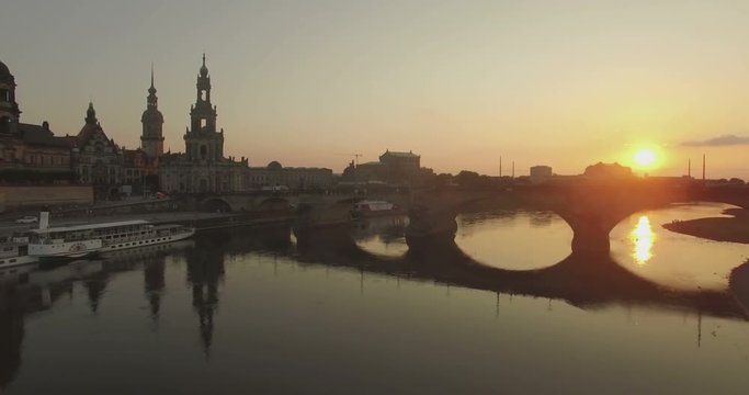 Aerial camera moves forward quickly to Augustusbruke in Dresden as the sun sets behind the bridge Traffic is crossing the bridge