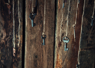 Many keys hanging on a string. Wooden background. Selective focus