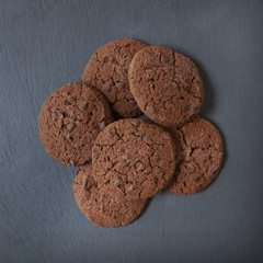 Aerial view of a pile of freshly baked chocolate chip cookies on a rustic slate background