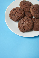 A plate of freshly baked chocolate chip cookies on a bright blue background forming a page border
