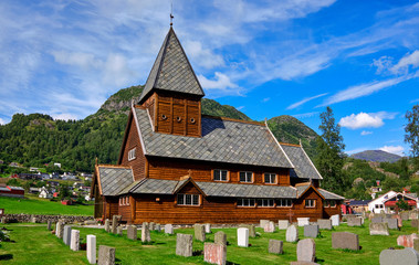 Fototapeta na wymiar Roeldal old wood stave church and belonging cemetery in front of the town houses in Norway