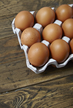 A tray of freshly laid hens eggs on a rustic wooden background
