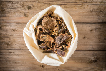 Dried mushrooms in a sack on a wooden table