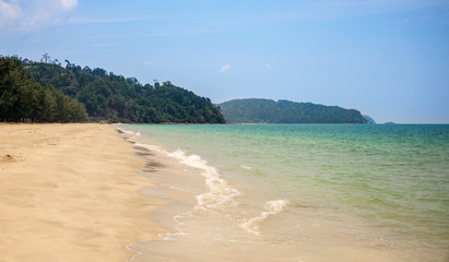 Lonely sandy beach. Green hills, blue sea, white sand