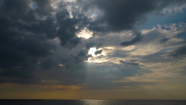 Sun rays through the clouds over the sea time lapse