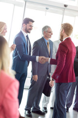 smiling business partners handshaking with leader.