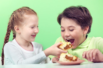 Little girl giving piece of pie to her boyfriend