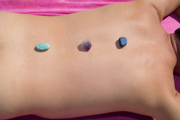 Crystal therapy, man's back on the beach having stone